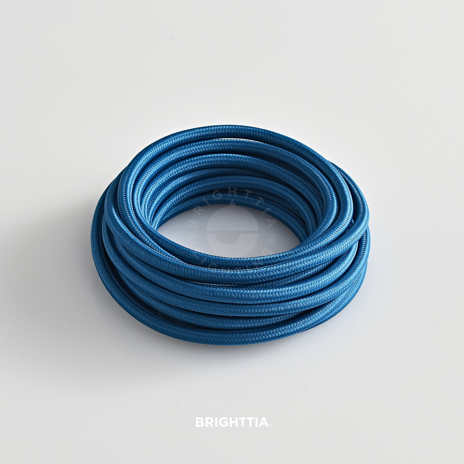 A roll of solid round aegean blue fabric cord 4.88m (16ft) on a white background