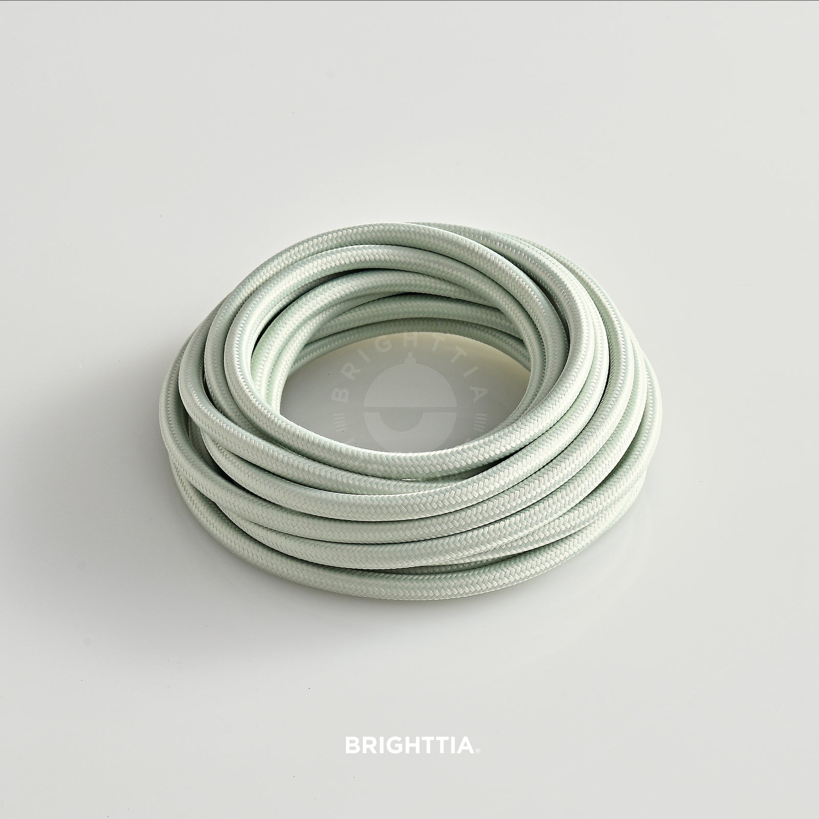 A roll of solid round pale green fabric cord 4.88m (16ft) on a white background