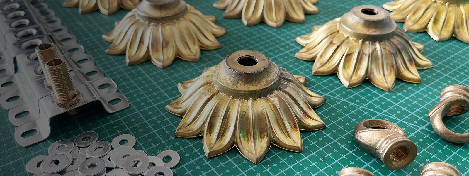 Brass flower ceiling hook being assembled on green surface before shipping