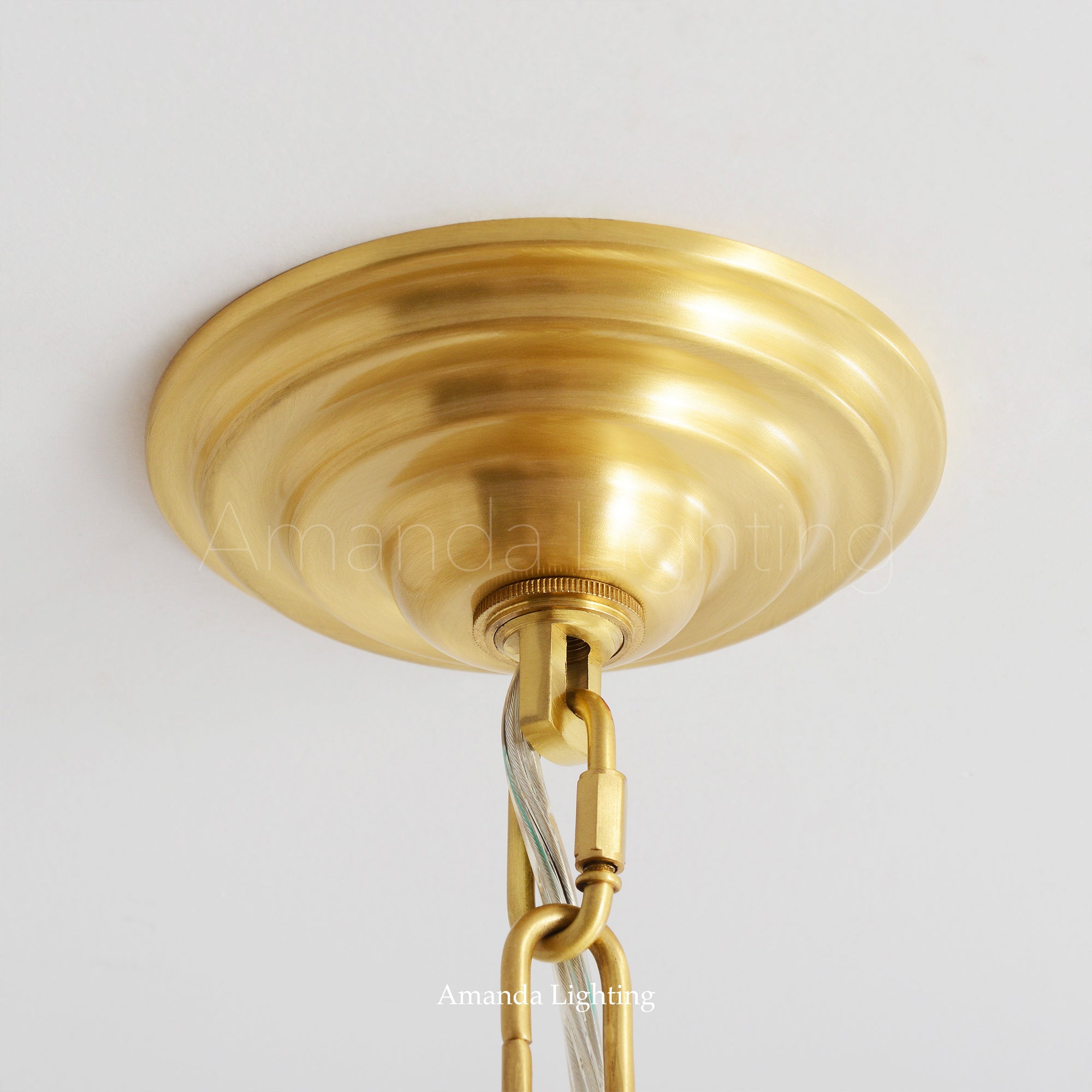 Detail of brass canopy on brass chandelier with white ceramic shade